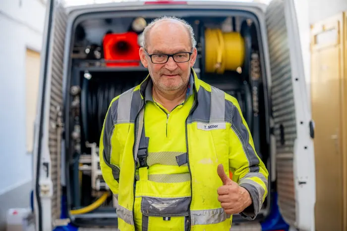 Mitarbeiter von KARO-Tec zeigt Daumen hoch vor dem Servicefahrzeug